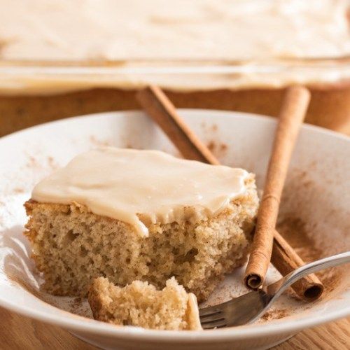 a piece of cake in a white bowl with cinnamon sticks