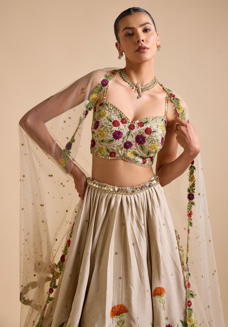 Elevate your ethnic wardrobe with Ivory Embroidered Lehenga. Crafted from luxurious silk, the lehenga features intricate thread, sequin, and cutdana embroidery in stunning floral patterns. Teamed with a modern cut embroidered strappy blouse and a beautifully adorned dupatta. This ensemble is ideal for a bride or bride-to-be, ensuring an unforgettable, elegant look for your special day. Composition : Skirt & Blouse - Silk, Dupatta - Net Care: Dry Clean Only and Vacuum Storage This product can be Tissue Silk Sets With Floral Embroidery For Reception, Anarkali Set With Floral Embroidery In Tissue Silk, Floor-length Lehenga With Floral Embroidery For Festivals, Designer Floral Embroidery Lehenga For Eid, Silk Sharara With Floral Embroidery For Festive Occasion, Floor-length Floral Embroidery Choli For Festive Occasions, Traditional Cream Sharara With Floral Embroidery, Festive Silk Sharara With Floral Embroidery, Floral Embroidered Sharara For Receptions And Festivals