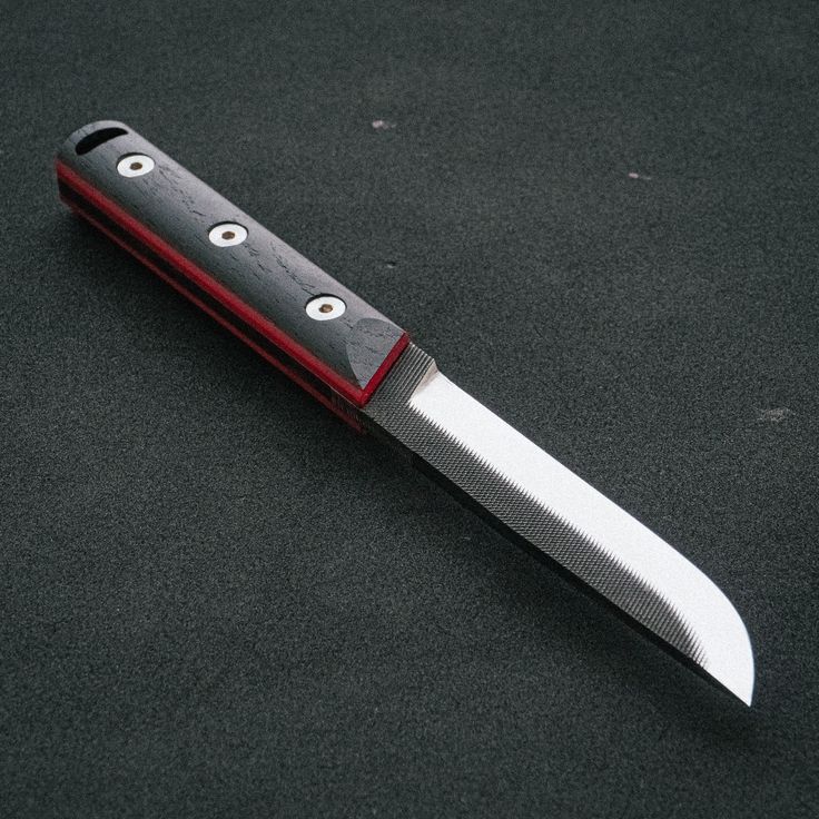 a red and black knife with two eyes on it's blade is laying on the ground