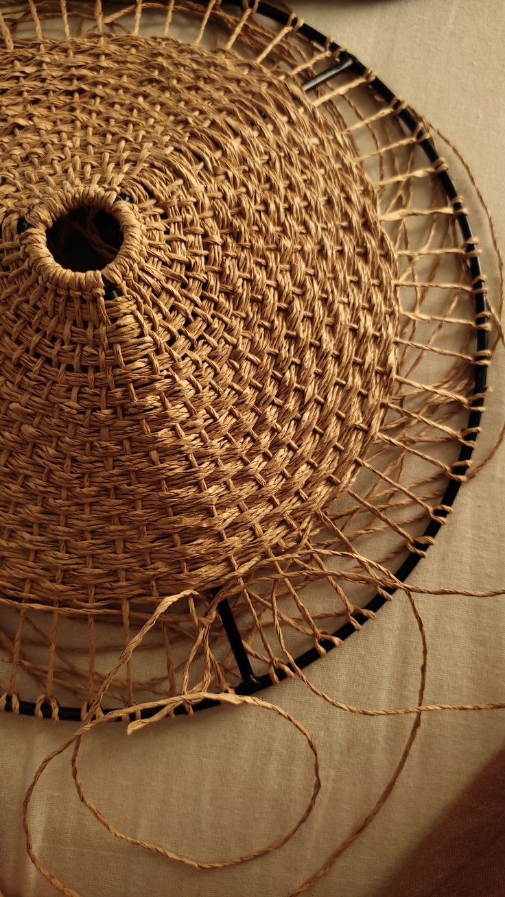 a woven basket sitting on top of a bed next to a wooden table with two plates and utensils