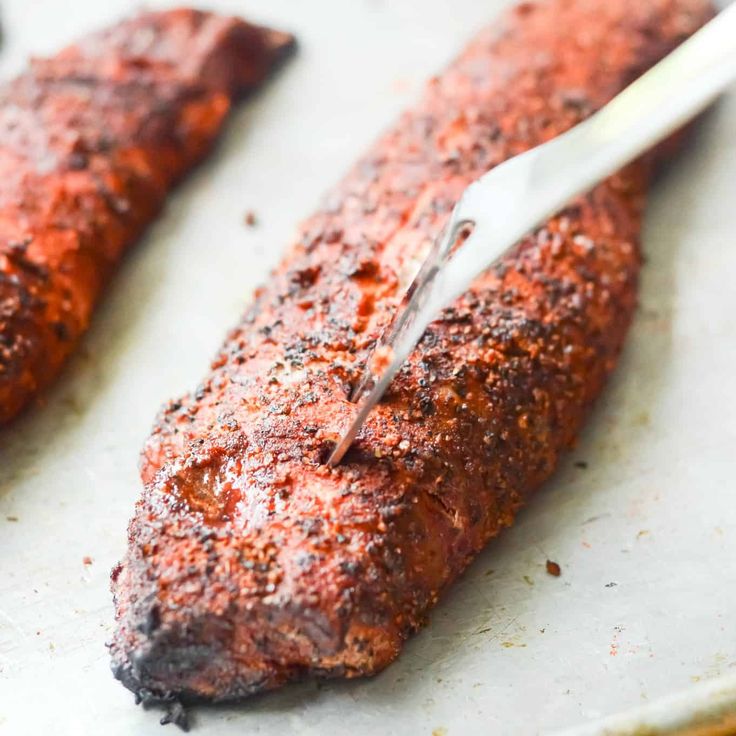 two steaks on a baking sheet with a knife sticking out of the top one