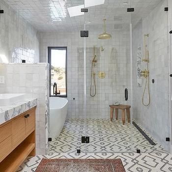 a bathroom with white tile and wooden cabinets, two sinks and a walk in shower