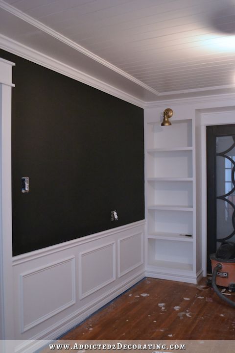 an empty room with black walls and white bookcases