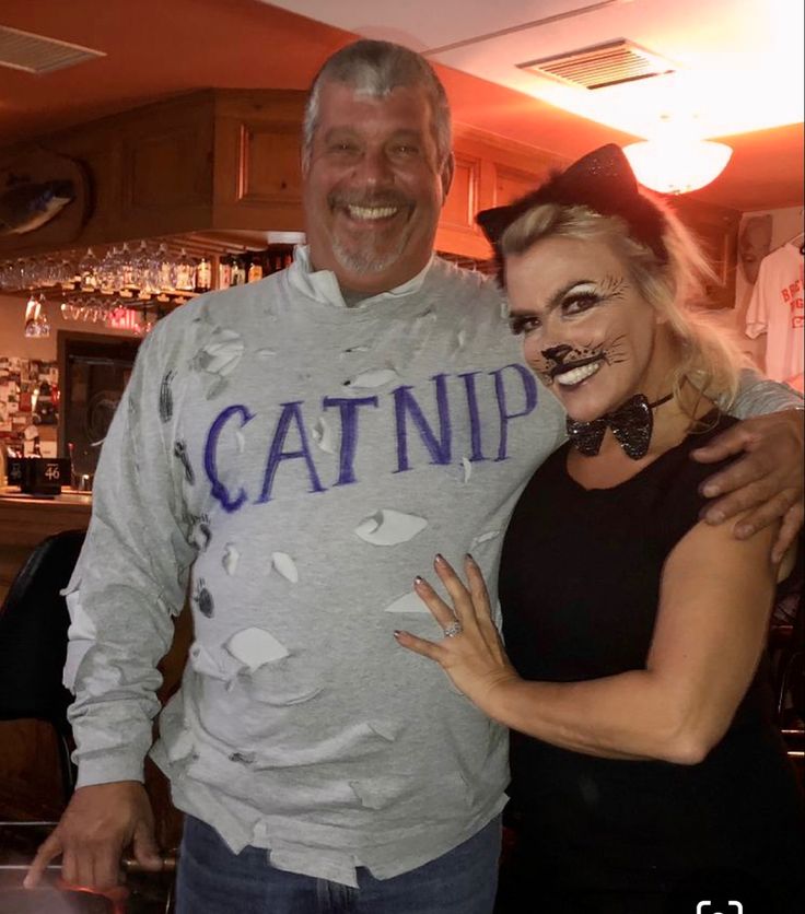 a man and woman pose for a photo in front of a bar with catnip on it