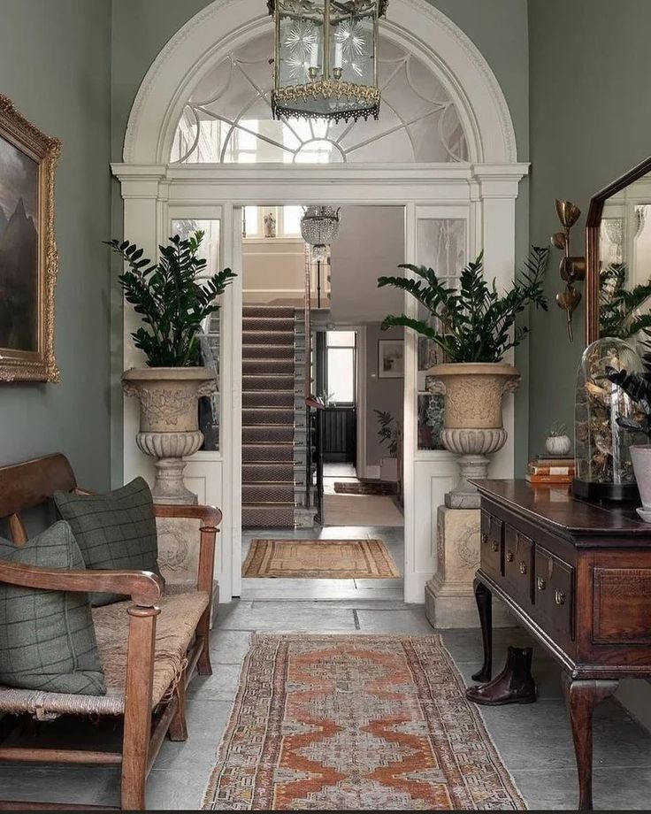 an entry way with green walls and white trim, wooden furniture and potted plants