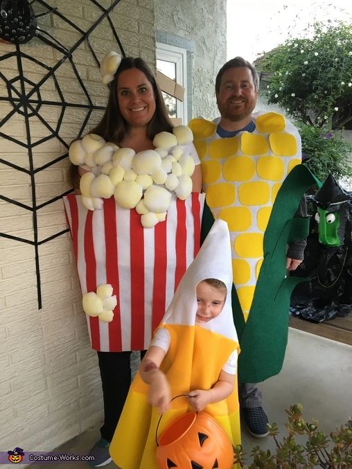 two people in costumes standing next to each other with pumpkins and corn on the cob