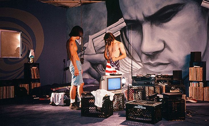 two men standing in front of a wall with a painting on it's side