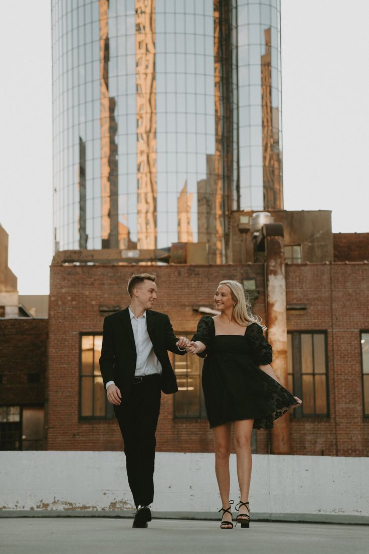 a man and woman walking in front of tall buildings