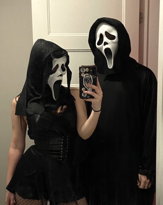 two people dressed up in halloween costumes taking a selfie with their cell phone while standing next to each other