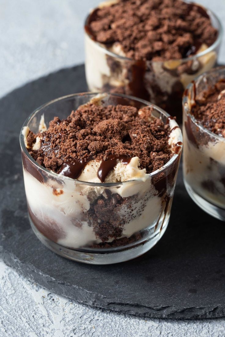 three desserts with chocolate and ice cream in small glasses on a slate platter