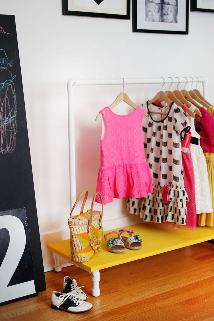 there is a yellow shelf with clothes and shoes on it next to a chalkboard