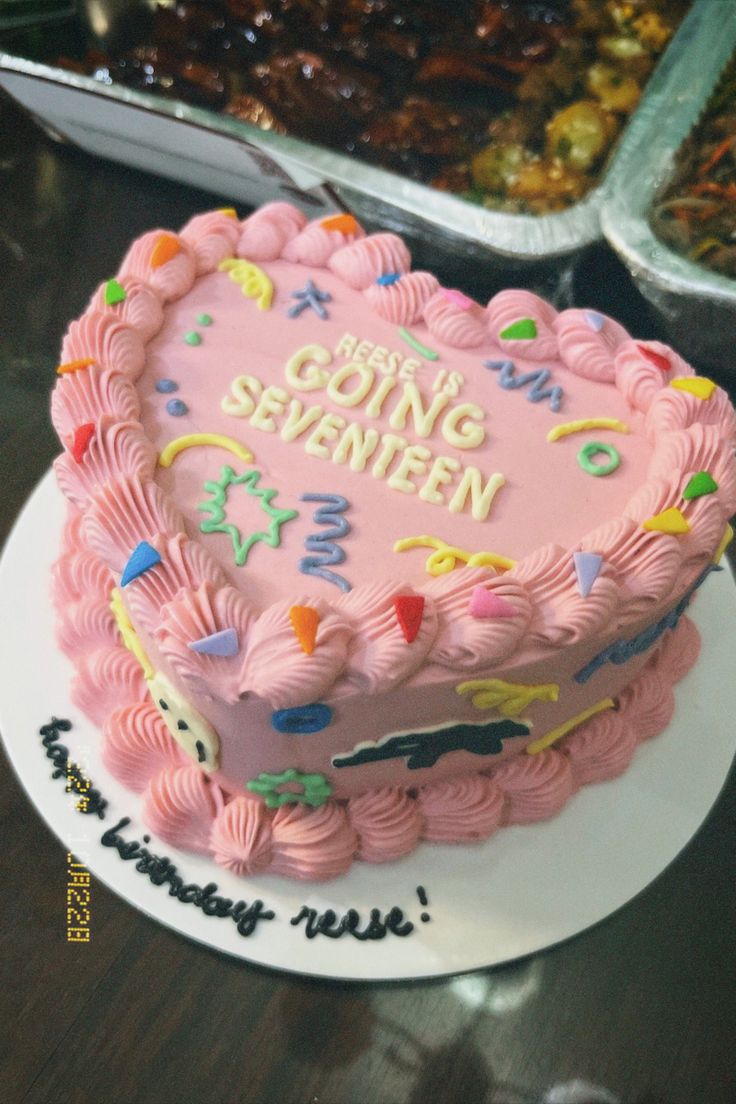 a pink heart shaped cake sitting on top of a table