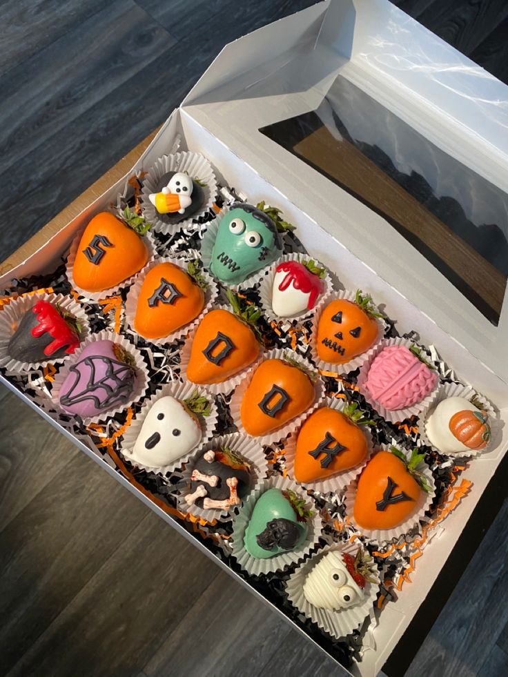 a box filled with halloween cupcakes on top of a wooden floor