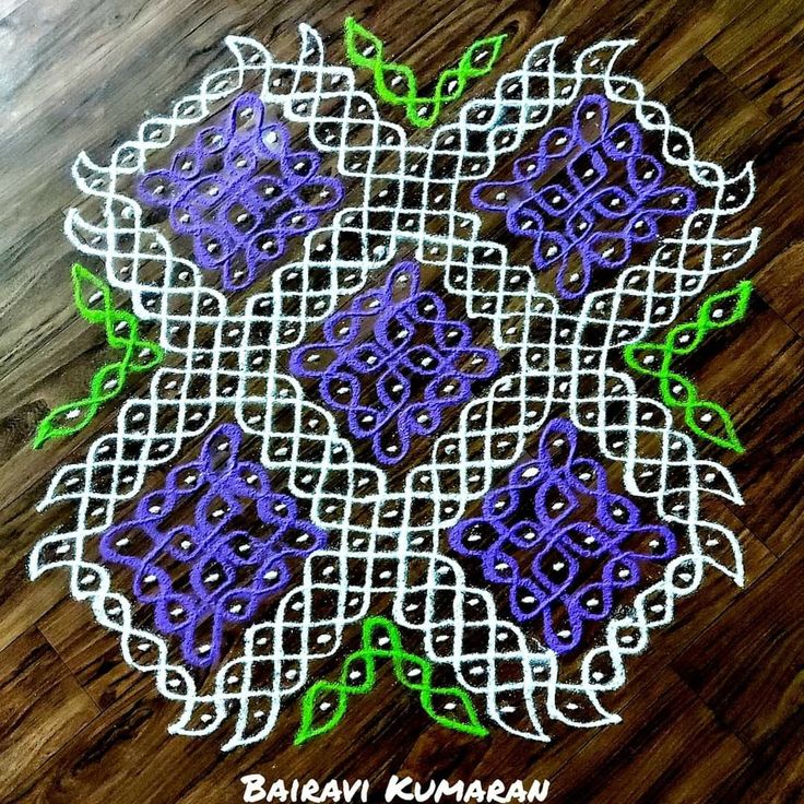 an intricately designed doily with green and purple flowers in the center on a wooden floor