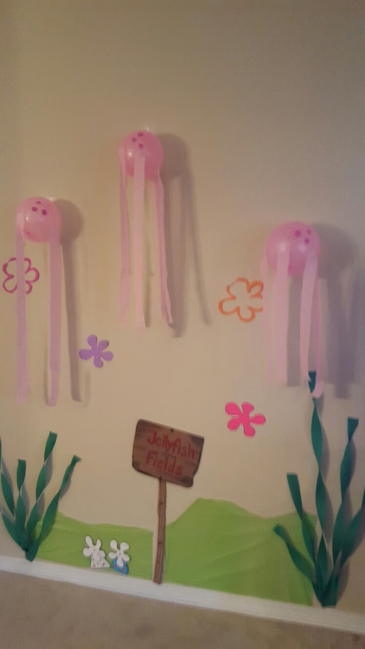 some pink jellyfish are hanging on the wall next to a sign that says happy birthday