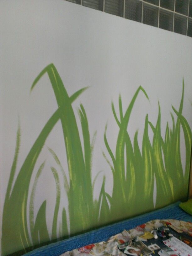 a bed with a painting on the wall and green grass painted on it's side