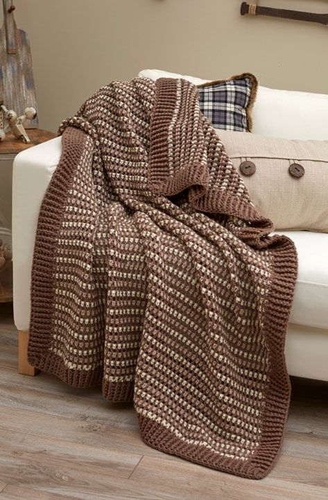 a brown and white blanket sitting on top of a couch