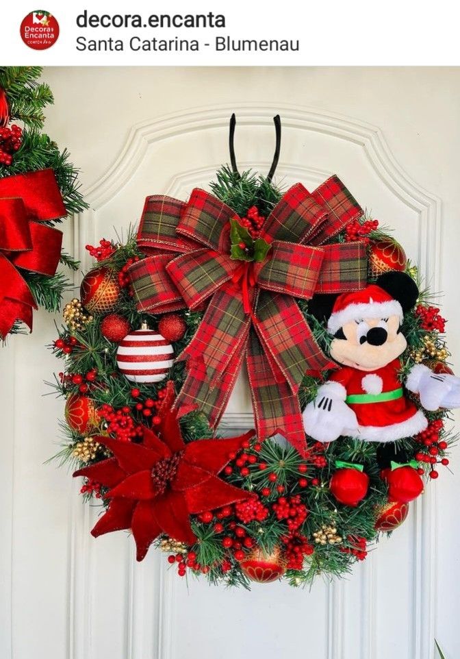 a christmas wreath is hanging on the front door with ornaments around it and a mickey mouse ornament