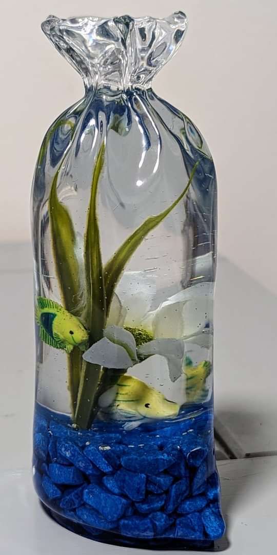 a clear bag filled with blue rocks and water next to a fish tank on top of a table