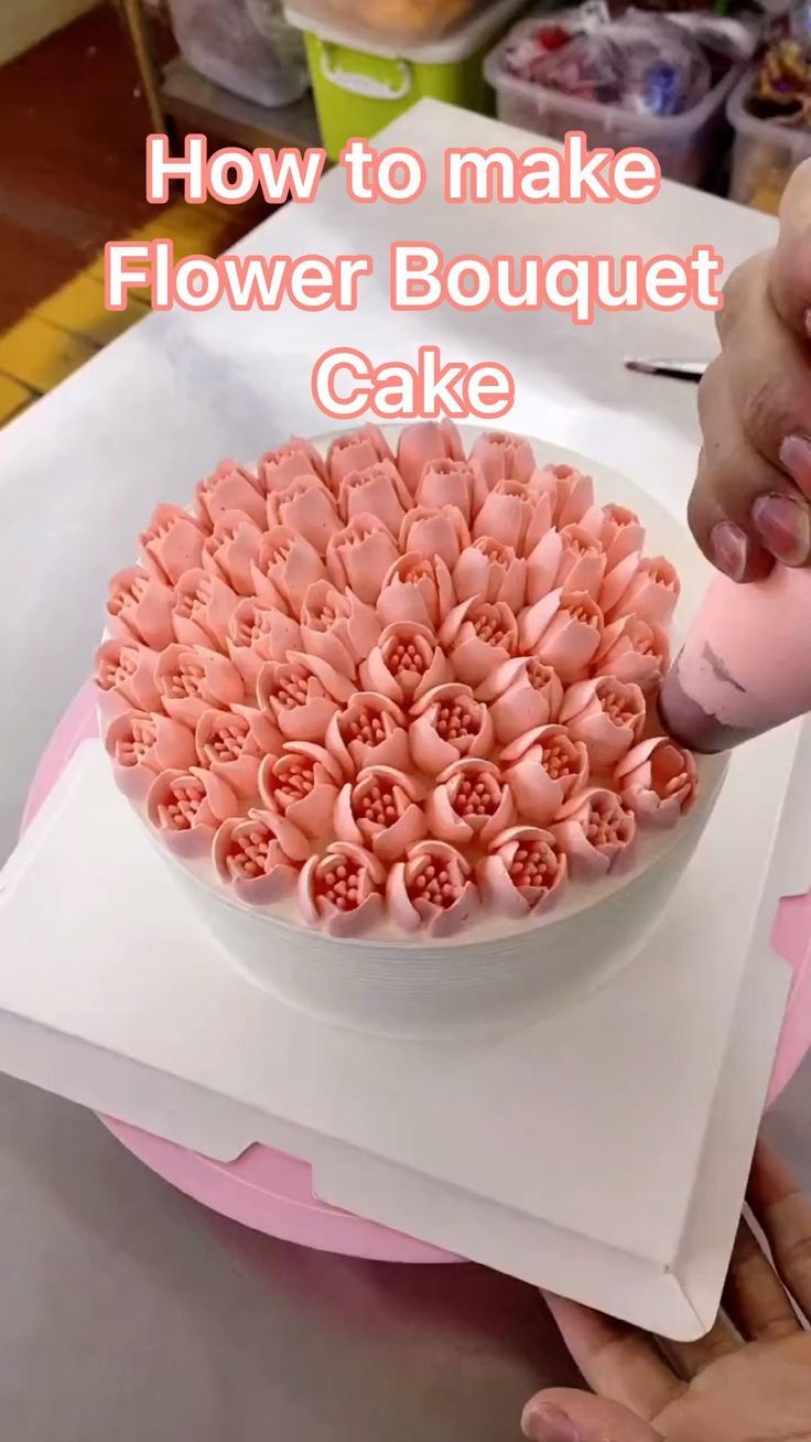 someone is decorating a flower bouquet cake with pink icing on the top and bottom