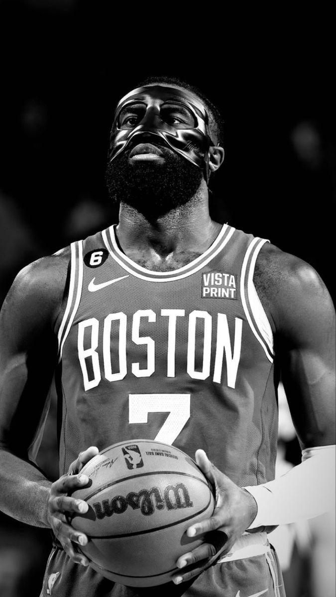 a man holding a basketball in his right hand and wearing a mask on top of it