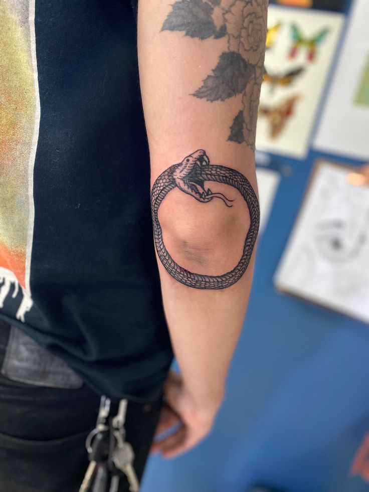 a person with a tattoo on their arm holding a snake in the middle of his arm