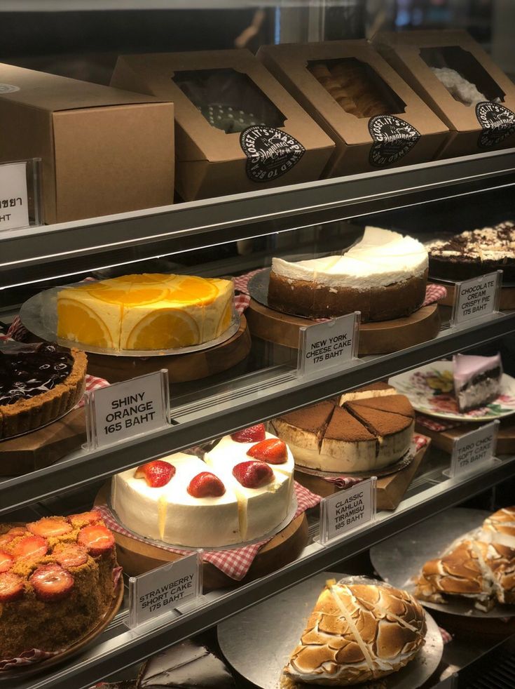 a display case filled with lots of different types of cakes and pies on plates