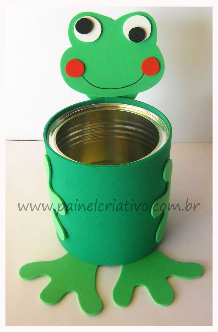 a green frog sitting on top of a metal cup