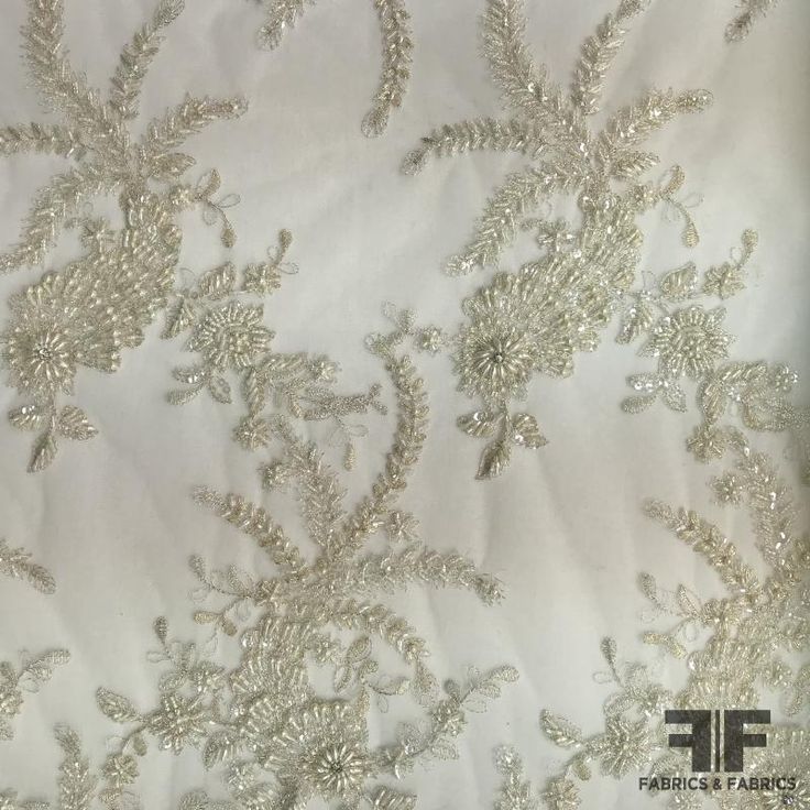 Couture Floral Beaded Netting - Ivory/Silver (Bridal) Color - White Ivory Silver Width - 50/51” Fabric Care - Dry Clean Only Elegant Cream Embroidered Fabric For Ceremony, Cream Wedding Fabric With Intricate Embroidery, Wedding Cream Embroidered Fabric With Intricate Details, Elegant Gold Wedding Dress With Zari Work, Elegant Gold Wedding Dress For Festive Occasions, Festive White Fabric With Pearl Embroidery, Festive White Embroidered Fabric With Pearls, White Pearl Embroidered Fabric For Mother Of The Bride, Elegant White Embroidered Fabric For Wedding