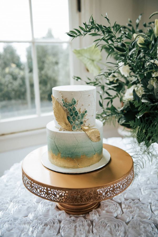 a three tiered cake sitting on top of a table next to a potted plant