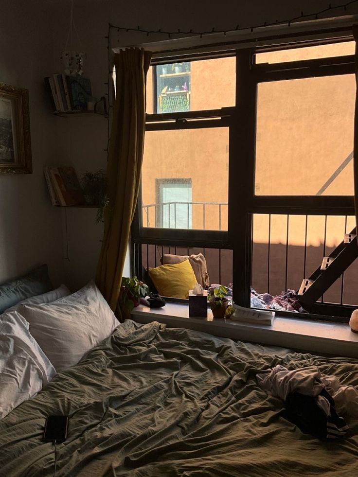 an unmade bed sitting in front of a window