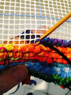 a person is holding a colorful piece of yarn with a crochet hook in it