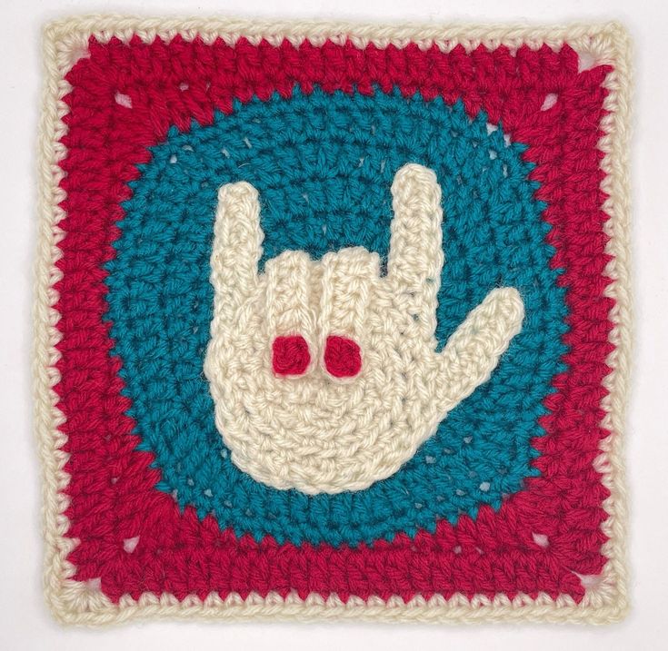 a crocheted square with a peace sign in the middle and two red eyes