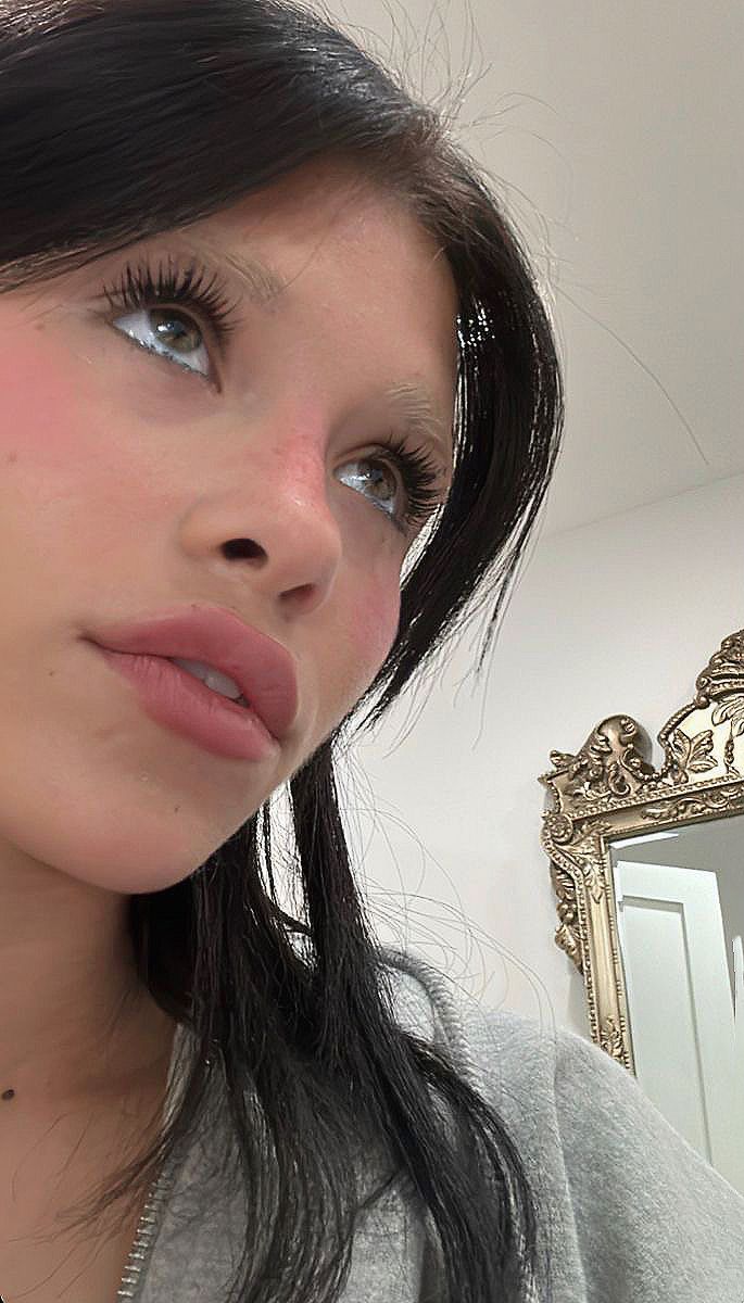 a woman is taking a selfie in front of a mirror with her hair pulled back