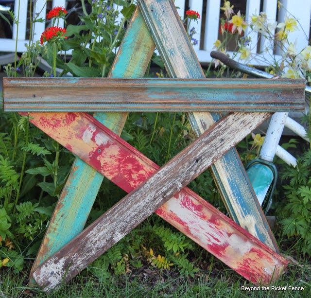 an old wooden bench sitting in the grass near flowers and other things on the ground