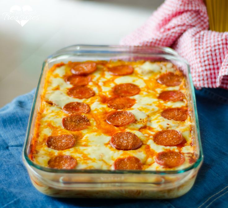 a close up of a pizza casserole in a glass dish on a person's lap