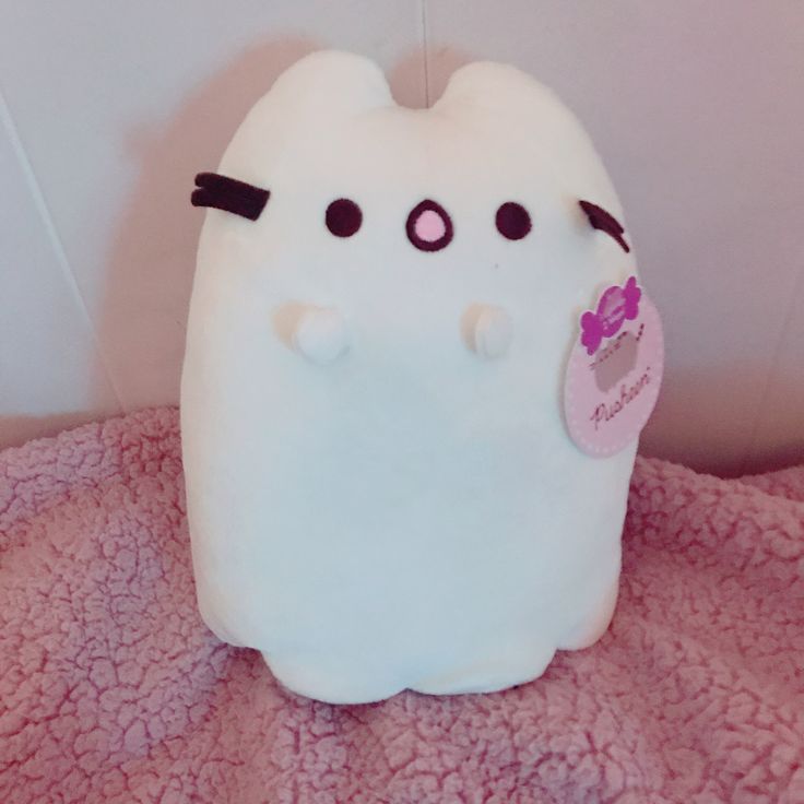 a white stuffed animal sitting on top of a pink blanket