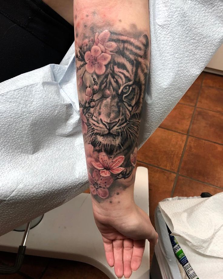 a person with a tiger tattoo on their arm holding onto a flowered wristband