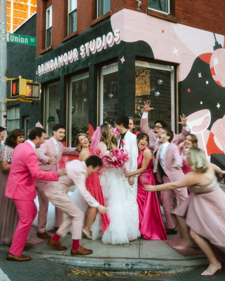 a group of people in front of a store with pink dresses and flower bouquets