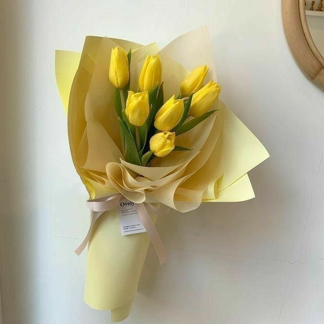 a bouquet of yellow tulips tied to a wall with a price tag on it