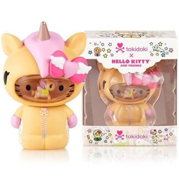 the hello kitty toy is in its box next to it's packaging, and has a pink hat on top