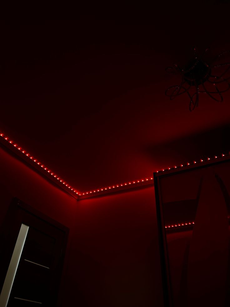 a red light shines on the ceiling in a dark room with a mirror and door