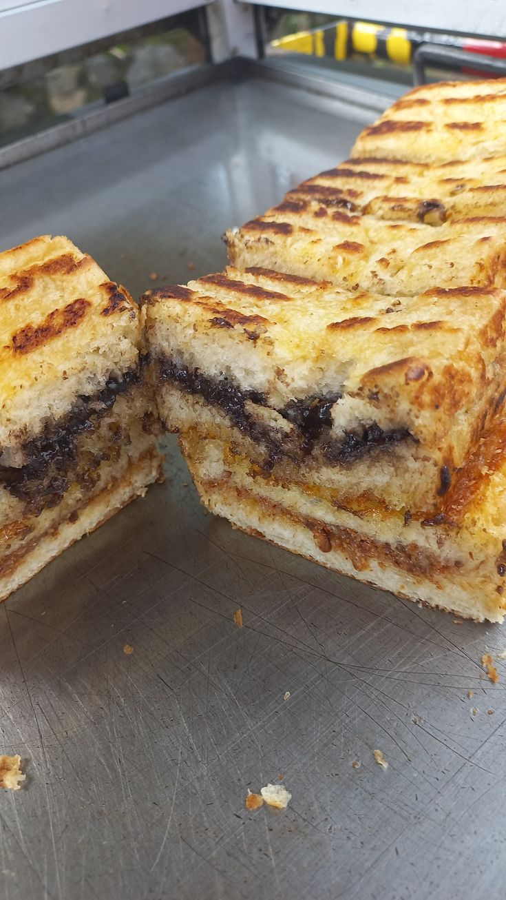 two grilled sandwiches sitting on top of a metal counter