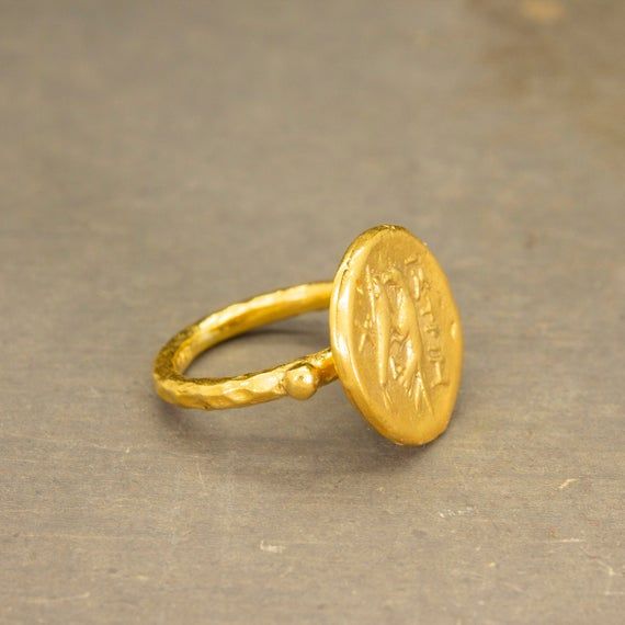 Ancient Art Hawk Signed Coin Ring made 24k gold plated 925 sterling silver and used Reproduction Bronze Coin.Our shop offer free ring sizing. Handcrafted hammered full round ring band size measures 2mm in width and 24k gold plated bronze coin 16.5x16.5 mm.Metal : 925 Sterling SilverBand Width : 2 mmCoin  : Reproduction Bronze CoinCoin Size : 16.5x16.5 mmRing Weight : 5.00 gramsRing Size : US 6 (The size you want is made for free).(We used the US standard sizing) **Custom Orders is Made**As pella Handmade Yellow Gold Ceremonial Rings, Handmade Yellow Gold Rings For Ceremonial Use, Handmade Yellow Gold Rings For Ceremonial Occasions, Handmade 22k Gold Ceremonial Rings, Handmade Symbolic Gold Signet Ring, Gold Hand Forged Signet Ring, Handmade 22k Gold Rings For Ceremonial Occasions, Handmade Gold Symbolic Signet Ring, Antique Hand-forged Gold Rings