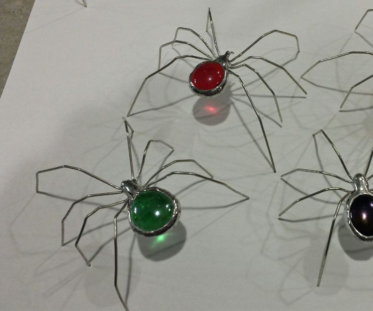 four metal spider sculptures sitting on top of a piece of paper with lights in them