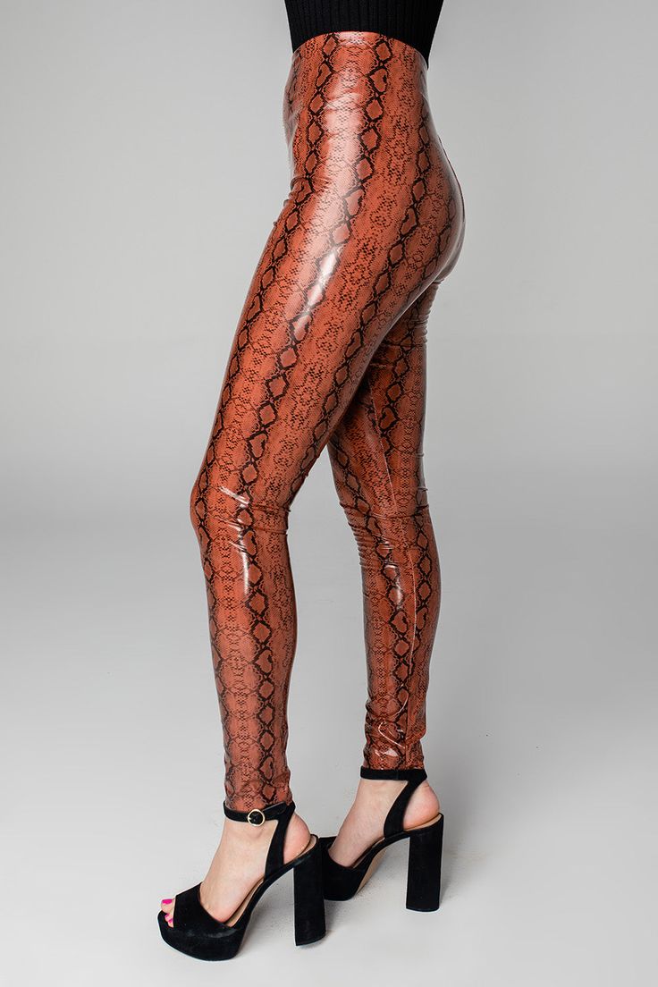 Our Mila Leggings will hold you in all the right places showing off your best asset. She features a patent vegan leather material, felt lining, and a sassy snake print to turn heads! Pair her with a graphic tee and combat boots or dress her up with a sweater and booties! Product Details: Fit: The Mila Leggings fit true to size. Length: Ankle length. Waist: Fitted - stretchy fabric allows custom fit. Hips: Fitted - stretchy fabric allows custom fit. Fabric: Fabric contains stretch. Self Material: Stretch Faux Leather Brown Bottoms, Stretch Brown Faux Leather Bottoms, Brown Stretch Leather Bottoms, Trendy Faux Leather Brown Leggings, Brown Stretch Leather Pants, Trendy Brown Faux Leather Leggings, Brown Stretch Leather Trousers, Stretch Brown Leather Trousers, Brown Stretch Leather Pants For Party