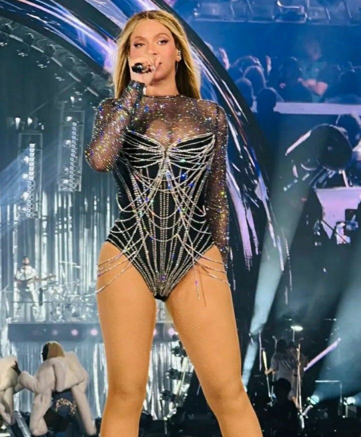 a woman in a bodysuit on the stage with microphone and twitter post about her performance