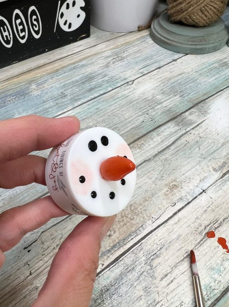 a person holding a small snowman made out of toilet paper on a wooden table