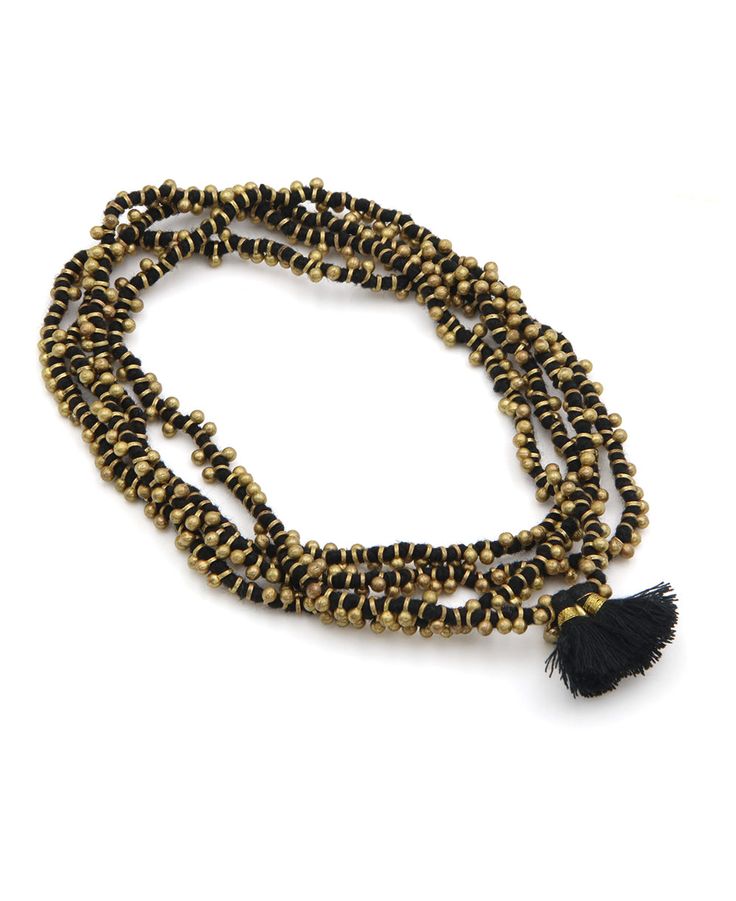 Add a touch of metallic radiance with our Manaka necklace. Golden baubles line its soft cotton strand while playful tassels add a traditional touch. An extra long length lets you wrap it multiple times for multiple styling options. Available in two easy-to-wear colors, every necklace is handmade by women artisans in India. Golden Manaka necklace Plated metal, brass, cotton thread Measures 46'' around Available in two colors Handmade in India This item may feature slight variations in color, fini