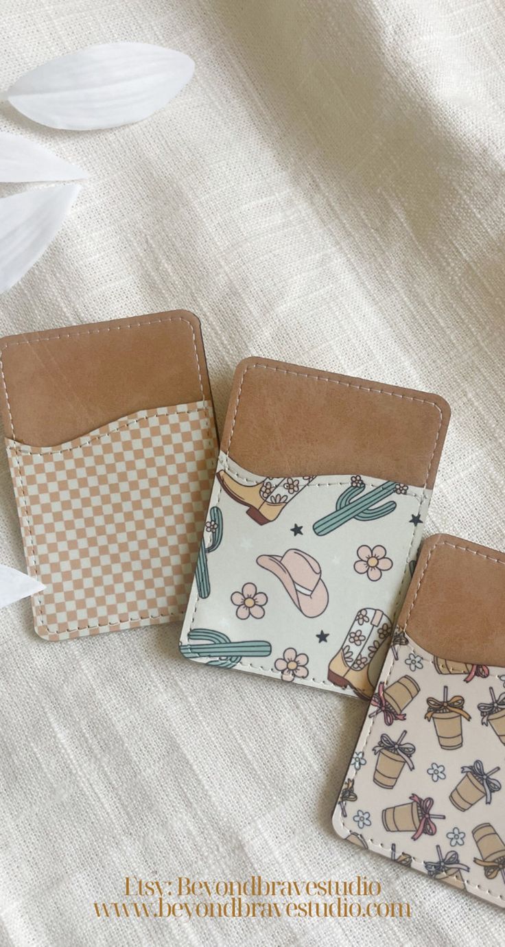 three small wallets sitting next to each other on a white cloth covered tablecloth